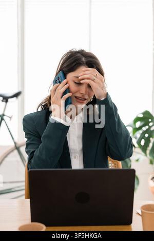 Stressed business woman talking phone having headache Stock Photo