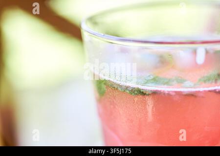 Close-up of a refreshing glass of cold raspberry lemonade with fresh mint leaves and condensation on the surface. Stock Photo