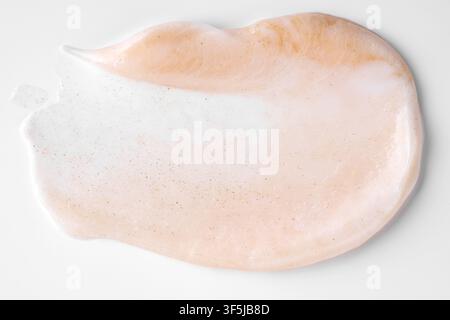 Close-up of a pearlescent cosmetic smear with subtle gold texture on a clean white background. Soft pink cream creates an elegant luxury beauty and sk Stock Photo