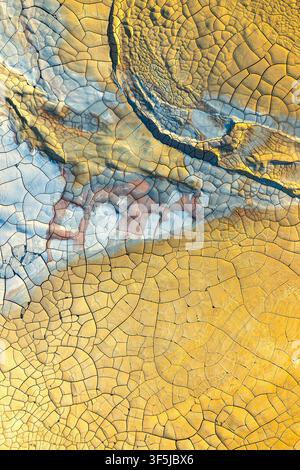 Aerial view of vibrant mineral textures and cracked earth patterns, showcasing an intricate blend of colors and textures that resemble abstract art in Stock Photo