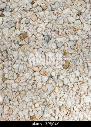 Close-up overhead view of pale white gravel embedded in rough cement, forming a detailed natural stone texture background suitable for construction, l Stock Photo