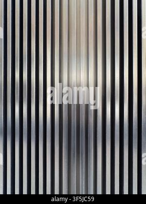 Close-up abstract background of narrow vertical metallic stripes in silver, gray, and black, creating a reflective industrial texture with strong line Stock Photo
