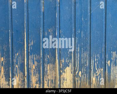 Close-up of weathered blue painted wooden planks with peeling paint and exposed natural grain, creating a rustic distressed texture for background or Stock Photo