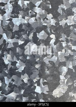 Abstract gray camouflage texture formed by overlapping light and dark paint fragments, creating a weathered layered surface with rough tonal variation Stock Photo