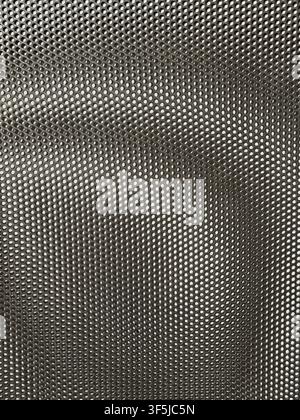 Close-up abstract background of dark perforated metal mesh with repeating circular holes, creating a detailed industrial texture, geometric pattern, a Stock Photo