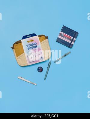 A colorful assortment of stationery, pens, sketchbooks, and pouch flat lay arranged on a blue surface studio shot. The scene evokes a relaxed, creativ Stock Photo