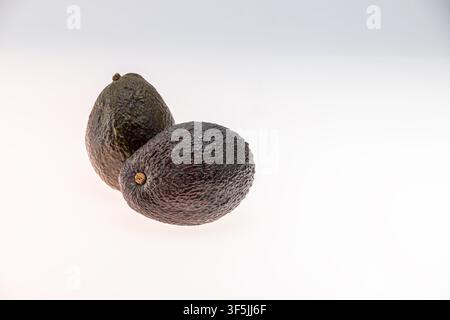 Wide horizontal studio still life of two whole ripe avocados with more generous spacing on a white background compared to the closer version. The wide Stock Photo