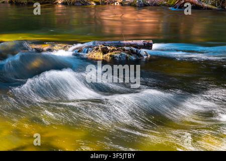 Abstract nature background featuring silky smooth water flowing over river rocks Stock Photo