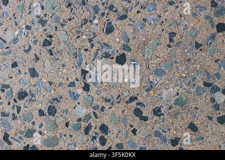Top view of outdoor grey terrazzo flooring with natural stone aggregates weathered architectural surface texture and seamless background. Stock Photo