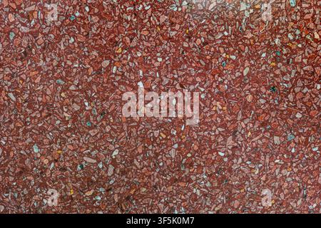 Top view close up of a polished red terrazzo stone texture with marble and granite chips, used for luxurious contemporary interior flooring. Stock Photo