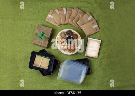 Microgreens growing kit with seed packets, jute mats, and trays on green background. Seed packets and growing supplies in flat lay composition on gree Stock Photo