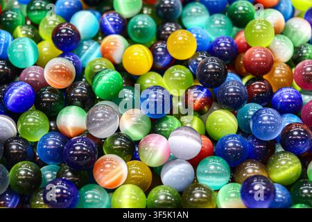 Close up overhead view of colorful transparent glass marbles forming an abstract textured background with glossy reflections and vibrant colors. Stock Photo