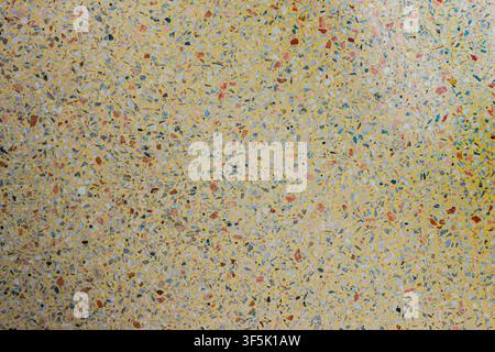 Cream yellow terrazzo floor texture with natural stone fragments photographed from above, suitable for architectural and design reference. Stock Photo