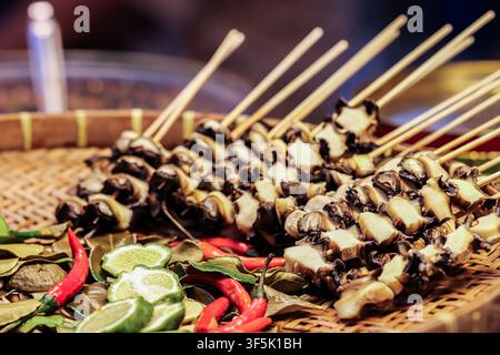 Thai style steamed mushroom skewers with kaffir lime, herbs and red chili arranged on a natural woven bamboo basket for local food culture Stock Photo