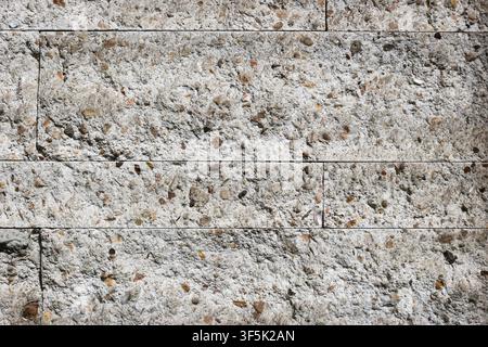 Rough light terrazzo wall with natural stone aggregate and horizontal panel joints, showing an architectural surface used in modern buildings. Stock Photo