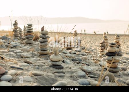 Balanced stone cairns on a sandy beach at sunset Stock Photo