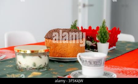 Panettone cake and coffee served on a festively decorated dining table for a New Year breakfast at home, with candle, table decorations and cozy indoo Stock Photo