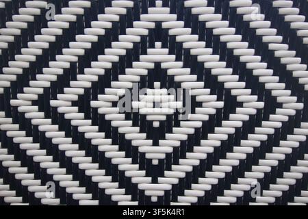 Close-up of a black and white woven surface with a geometric diamond pattern, resembling synthetic wicker weave texture. Stock Photo