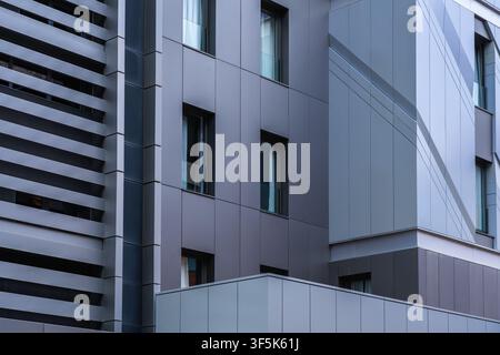 Close-up of a modern building facade featuring sleek metal panel cladding, crisp lines, and vertical windows, showcasing contemporary architectural de Stock Photo