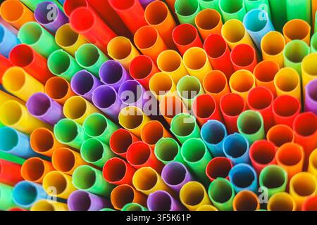 View of colorful plastic drinking straws arranged tightly together, creating a vivid abstract texture with repeated circular shapes and bold colors. Stock Photo