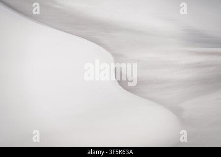 Close-up view of soft white sand dunes in Argentina, showing smooth wind-shaped ridges, subtle shadows, and fine natural texture in an abstract desert Stock Photo