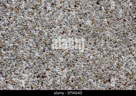 Fine stone aggregate terrazzo wall surface with speckled pebble texture on a modern building exterior, suitable for architectural publishing. Stock Photo
