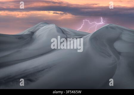 Dramatic lightning illuminates storm clouds above sculpted Saujil Dunes in Catamarca, Argentina, revealing a remote desert wilderness at sunset with m Stock Photo