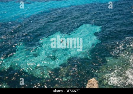 Sunlit turquoise Mediterranean seawater ripples above submerged rocks near Favignana, Sicily. Gentle waves, sparkling reflections, and clear blue wate Stock Photo