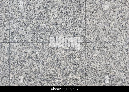 Light grey granite floor tiles with visible grid seams and speckled mineral texture on an outdoor walkway, suitable for architectural publishing. Stock Photo