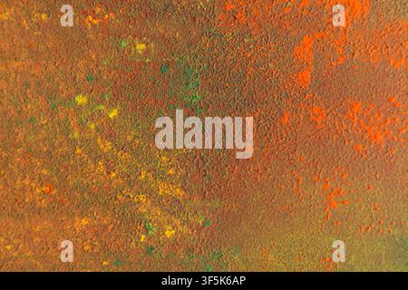 Close-up abstract art texture featuring weathered orange, green, yellow and brown paint. Rich cracked surface pattern creates a bright autumn-inspired Stock Photo