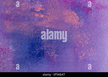 Vibrant abstract background featuring a rough textured surface in purple, blue, and magenta tones, enhanced by scattered orange accents for a dramatic Stock Photo