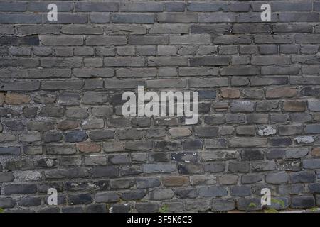 This high-resolution texture showcases an aged grey brick wall with rough, uneven surfaces and visible weathered cement mortar between each block. The Stock Photo