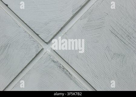 Close up of a pale grey textured wall surface with diagonal grooves forming a crossing diamond pattern, abstract background. Stock Photo