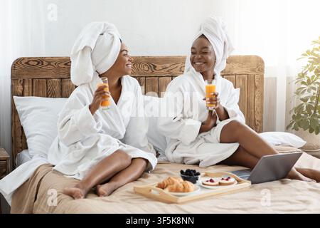 Happy black female friends having breakfast in bed Stock Photo