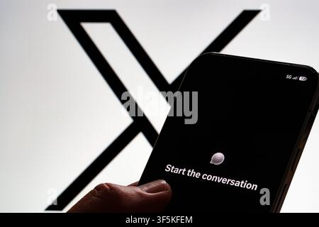 XChat welcome screen shown on a smartphone held in hand against a large X logo on a monitor. Stafford, United Kingdom, August 2, 2026. Stock Photo