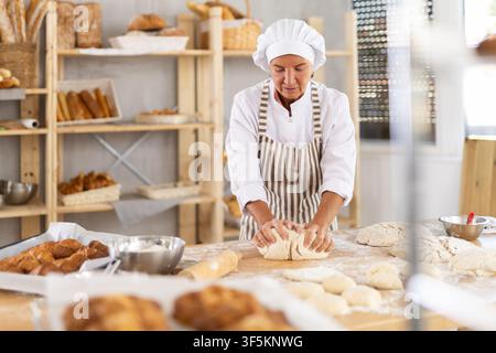 Elderly female baker working diligently in a bakery Stock Photo