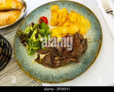 Pork fillet in homemade marinade with fried potatoes and green salad Stock Photo