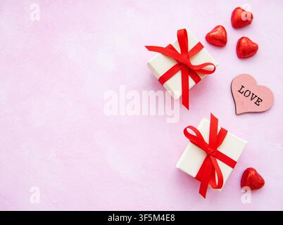 Valentines day romantic background - decorative hearts, gift boxes and candles on a pink marble background Stock Photo