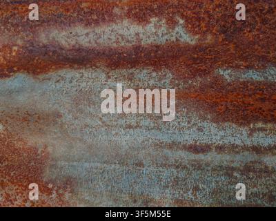 A textured close-up of a heavily rusted corrugated metal sheet featuring distinct orange, brown, and gray oxidation patterns. Stock Photo