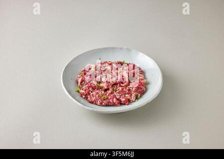 Korean seasoned ground beef or raw minced beef with green onion and seasoning served on a white oval plate on a light gray background, Korean food pho Stock Photo