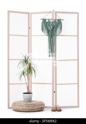 Boho chic room divider with macrame wall hanging, potted plant, and woven pouf, isolated on a white background Stock Photo