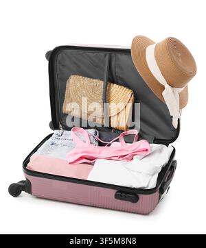 Open pink suitcase packed with summer clothes, straw hat, and clutch for vacation travel, isolated on a white background Stock Photo