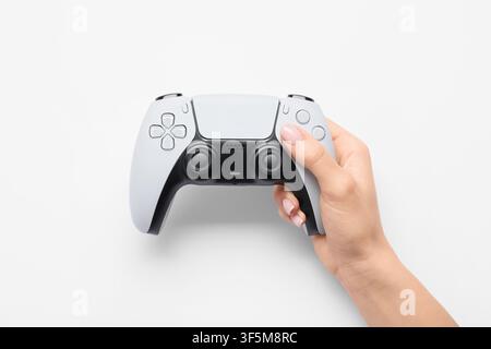 Female hand holding a modern white video game controller with black accents, gaming and entertainment concept, isolated on a white background Stock Photo