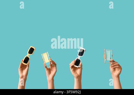 Female hands holding mini deck chairs with sunglasses on blue background Stock Photo