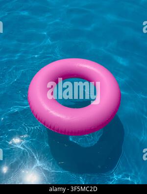 Pink float ring in clear swimming pool water on a sunny day Stock Photo