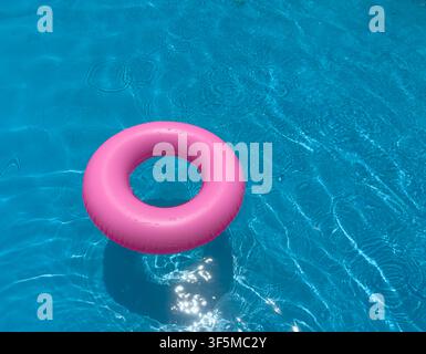 Pink float ring in clear swimming pool water on a sunny day Stock Photo