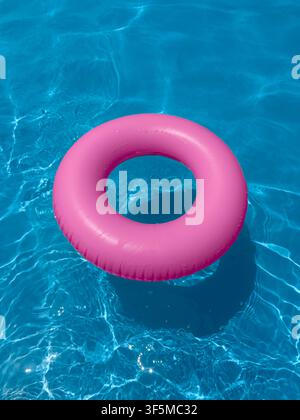 Pink float ring in clear swimming pool water on a sunny day Stock Photo