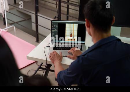 Photographer editing product photos on laptop in studio for post production Stock Photo
