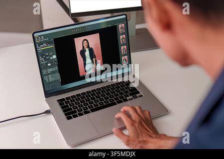 Photographer editing portrait photo on laptop computer at studio workspace Stock Photo