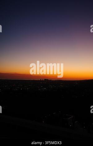 Dramatic orange-to-blue sunset gradient over the Los Angeles skyline from Griffith Park Stock Photo